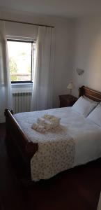 a bedroom with a bed with white sheets and a window at Casa Esquível in Mourão