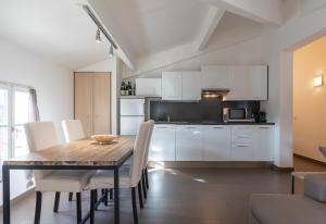 Una cocina y comedor con mesa de madera y gabinetes blancos. en Appartement DELICE B, en Saint-Tropez