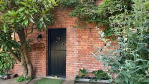 ein Backsteingebäude mit einer schwarzen Tür und einem Baum in der Unterkunft Shippen Cottage - Perfect for Couples or Families in Sidmouth