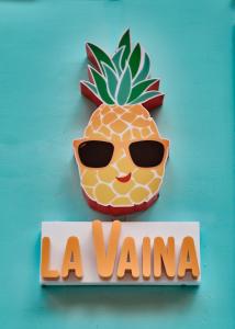 a sign for a store with a pineapple wearing sunglasses at La Vaina Cali in Cali