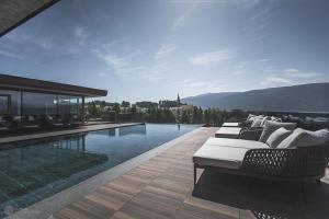 a swimming pool with lounge chairs next to a house at Terentnerhof 4*S active & lifestyle hotel in Terento