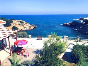 a patio with a red umbrella and chairs and the ocean at SEA & SKY Bungalows Escape Beach Guest Rooms in Kérynia +13 photos