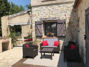 un patio con 2 sillas y una mesa con almohadas rojas en Mas du tilleul, en Callian