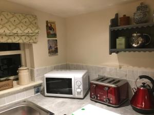 a kitchen with a microwave and a toaster oven at Ivy Todd cottage in Debden