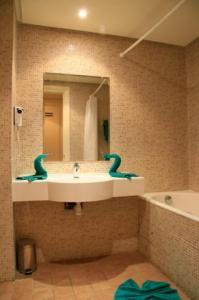 een badkamer met een wastafel, een spiegel en een bad bij Sufetula Hotel in Sbeitla