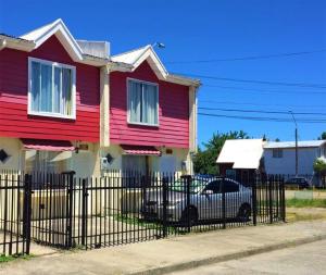 a red house with a car parked in front of it at Departamentos Egaña in Puerto Montt