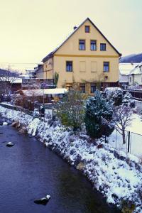 una casa con nieve en el suelo junto a un río en U Broučků en Lipova Lazne