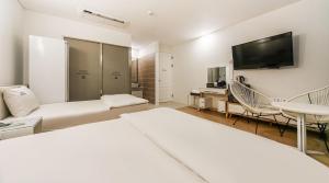 a hotel room with two beds and a flat screen tv at Hotel Insomnia in Daegu
