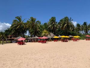 a beach with tables and chairs and umbrellas on it at Summit Pousada Noah in Maceió