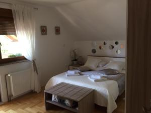 - une chambre avec un lit blanc et une table dans l'établissement Apartment Majetić, à Gornji Vaganac