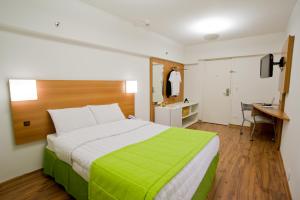 圣保罗Slim São Paulo Congonhas的卧室里有一张大床，上面铺着绿色毯子