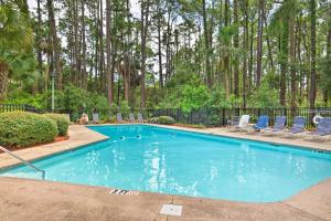 einen großen Pool mit Stühlen und Bäumen in der Unterkunft Remodeled Cottage on Sparrow Pond, Walk to Beach! in Kiawah Island