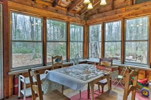una sala da pranzo con tavolo, sedie e finestre di East Otis Reservoir Cabin with Porch - Walk to Lake! a East Otis