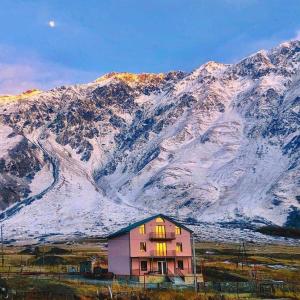 a house in front of a snow covered mountain at Hotel Diamond Kazbegi in Stepantsminda
