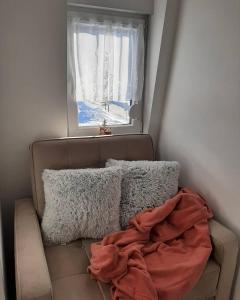 una coperta seduta su un divano sotto una finestra di Snowman Studio Apartment Jahorina a Jahorina