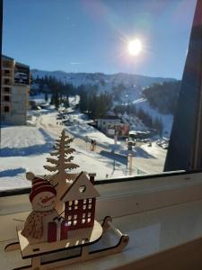 a christmas ornament of a snowman and a house in a window at Snowman Studio Apartment Jahorina in Jahorina