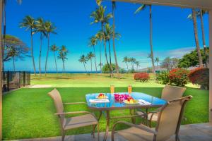 una mesa azul con comida en un césped con palmeras en Gorgeous Oceanfront Condo with Spectacular Views! en Kihei