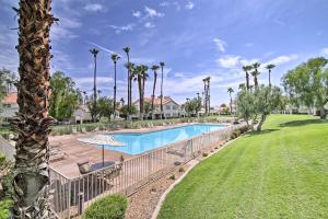 a swimming pool with a lawn and palm trees at Palm Desert Country Club Home with Patio and Grill! in Palm Desert