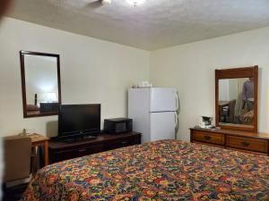 a bedroom with a bed and a tv and a refrigerator at Nakon Motel in Candler