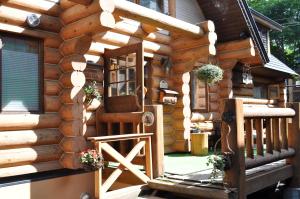 une cabane en rondins avec un escalier menant à une terrasse couverte dans l'établissement Pension Woody Note, à Niseko