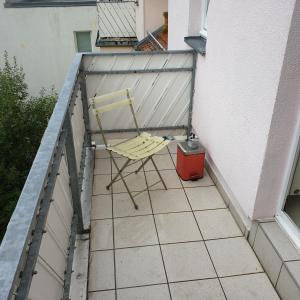 une chaise jaune assise sur un balcon dans l'établissement Kunstgasse 11, Wohnung 10, à Altenburg