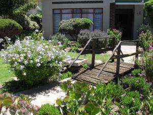 un jardín con un puente de madera frente a una casa en Eagle's Nest en Graaff-Reinet