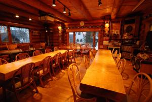 a dining room with wooden tables and chairs at Pension Woody Note in Niseko