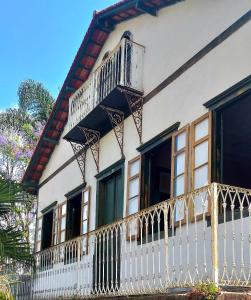 a house with a white fence and a balcony at Hostel Pousada Harpia in Passa Quatro