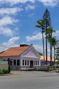 a white building with a red roof and palm trees at Namoa Pollastrini in Itanhaém
