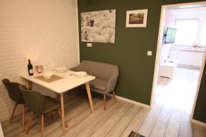 comedor con mesa, sillas y pared verde en Ferienwohnung Heide en Scheeßel