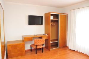 Habitación con escritorio, TV y silla. en Hotel Frasi's en San Clemente del Tuyú