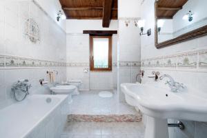 Casale Le Orme في تودي: حمام ابيض مع مغسلتين ودورتين مياه