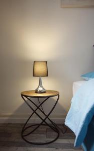 a table with a lamp on it next to a bed at " Le Léana Cardi " Fécamp Bord de mer in Fécamp