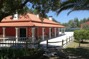 ein rotes Haus mit einem Zaun davor in der Unterkunft Quinta do Sobreiro, 4 bedroom Modernised Farmhouse in Tomar