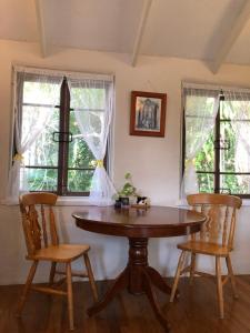 une table et deux chaises dans une pièce avec des fenêtres dans l'établissement Karma Cottage, à Maleny