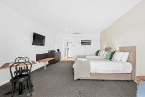 a bedroom with a bed and a desk and a table at 13th Beach Golf Lodges in Barwon Heads