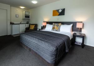 a bedroom with a large bed and a kitchen at Airport Palms Motel in Christchurch