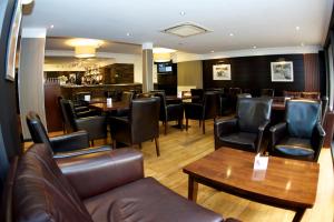 a restaurant with leather chairs and tables and a bar at Nevis Bank Inn in Fort William