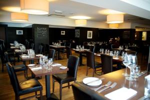 a dining room with tables and chairs with glasses at Nevis Bank Inn in Fort William