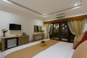 a bedroom with a large bed and a television at Puri Payogan Villa in Ubud