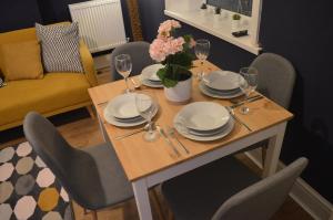 a table with plates and glasses and a vase of flowers at 9 bed house (7 Mins) 2 miles from Newcastle centre in Newcastle upon Tyne