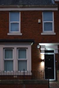 uma casa de tijolos com uma porta preta e janelas em 9 bed house (7 Mins) 2 miles from Newcastle centre em Newcastle upon Tyne
