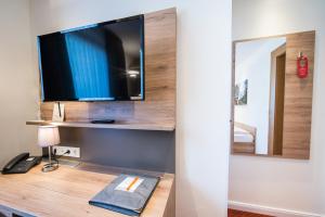 een kamer met een televisie op een bureau met een spiegel bij Hotel Hanses-Bräutigam in Schmallenberg