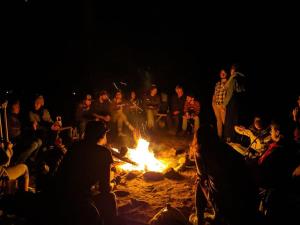 Un groupe de gens assis autour d'un feu dans l'établissement Auberge de jeunesse du Domaine à Liguori, à Petite-Rivière-Saint-François