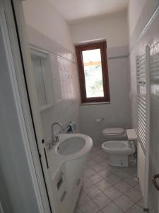 bagno con lavandino, servizi igienici e finestra di Appartamento Il Sole a Marina di Campo