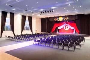 ein großes Zimmer mit Stühlen und einer Bühne mit einer Bühne in der Unterkunft Palm Beach Club Marmara Djerba in Midoun