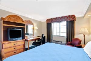 a hotel room with a bed and a desk and a television at Days Inn by Wyndham San Antonio Airport in San Antonio