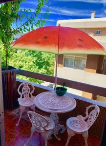 a table and chairs with an umbrella on a balcony at Coffee Cream Guest House Maia in Maia