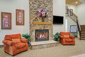 sala de estar con 2 sillas y chimenea en Super 8 by Wyndham Rogers Minnesota, en Rogers