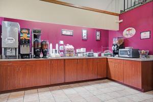 un restaurante con una barra y una pared rosa en Super 8 by Wyndham Rogers Minnesota, en Rogers